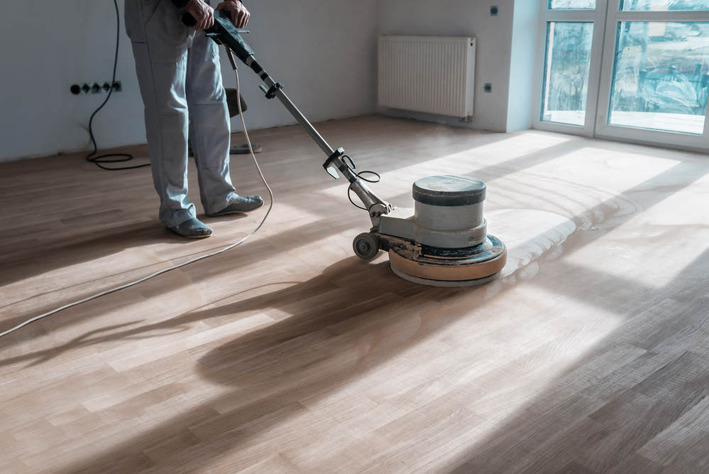 a professional master cleans the floor (parquet) with a polishing machine